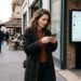 Une femme regarde son téléphone, surprise, devant un écran de checkout Shein affichant une ligne de taxe supplémentaire sur
