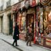 Une devanture de boutique éphémère dans une rue pavée du Marais, vitrine habillée aux couleurs de la collection Zara x John